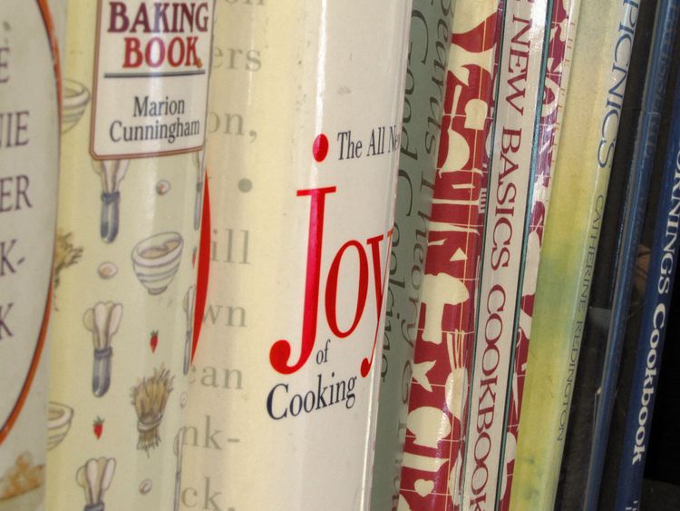 Classic cookbooks on a shelf:  The Joy of Cooking, Fannie Farmer cookbook, etc.
