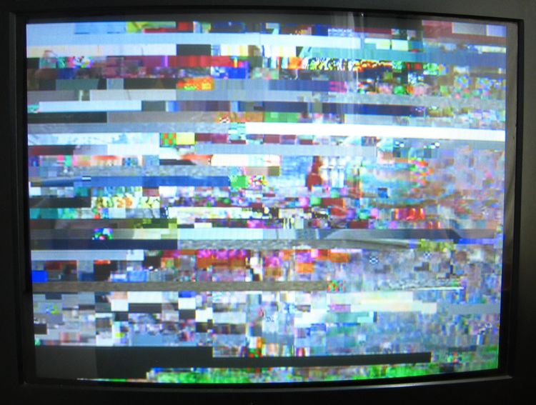 TV screen, showing colorful, quiltlike pixilation, lots of blues and greens with splashes of red and black