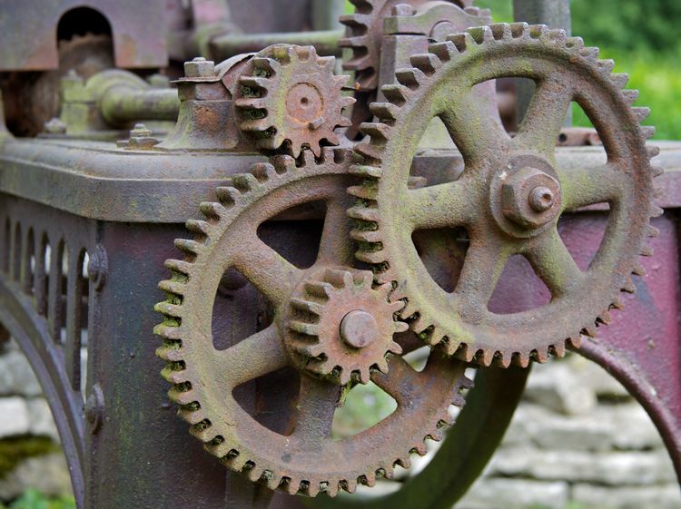 Weathered interlocking gears of various sizes, in a larger machine.