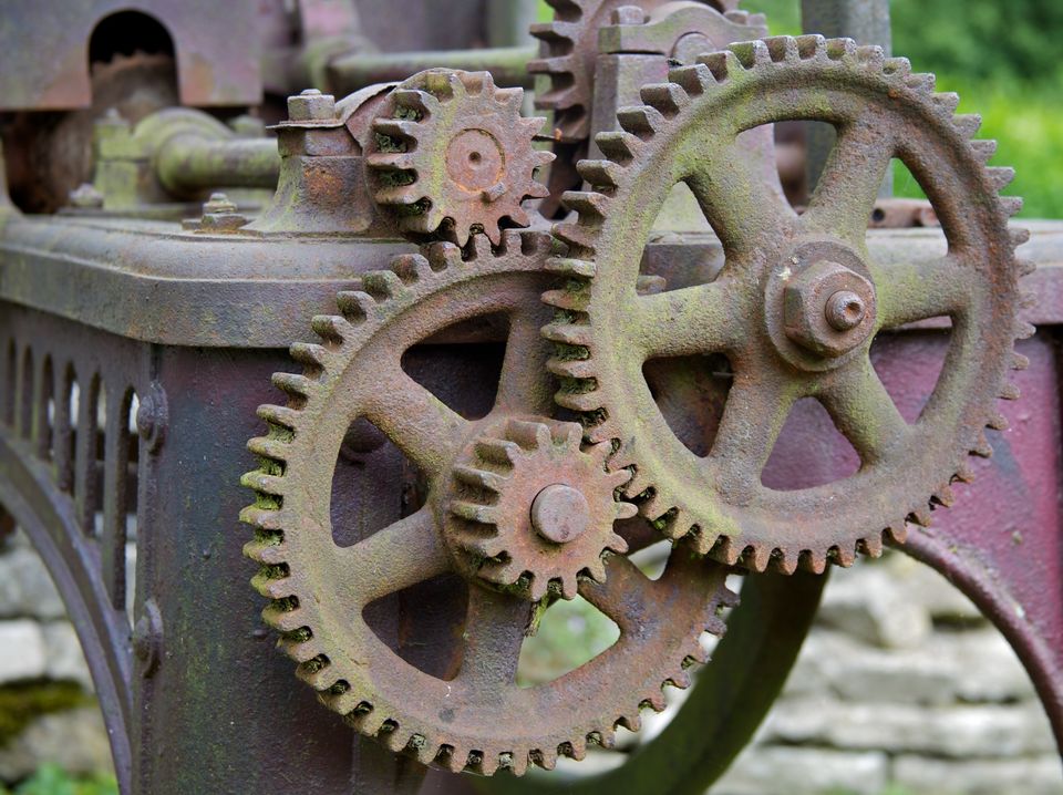 Weathered interlocking gears of various sizes, in a larger machine.