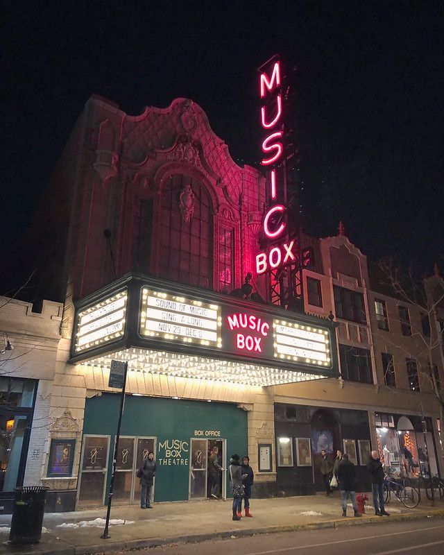 Chicago's Music Box theatre on an early winter night, neon sign, marquee, people bundled up, bits of snow on the sidewalk.