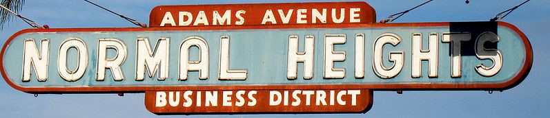 Neon sign, not lit, white letters, blue and red background, "Normal Heights, Adams Avenue Business District"