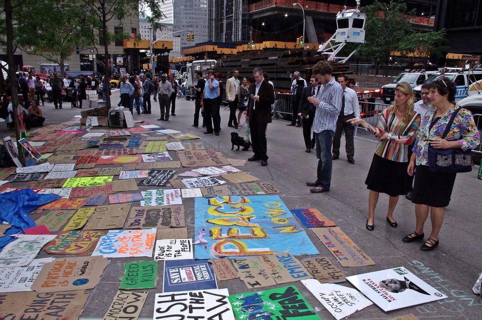 Office workers line up to look at a quilt-like arrangement of Occupy Wall street posters and banners. 